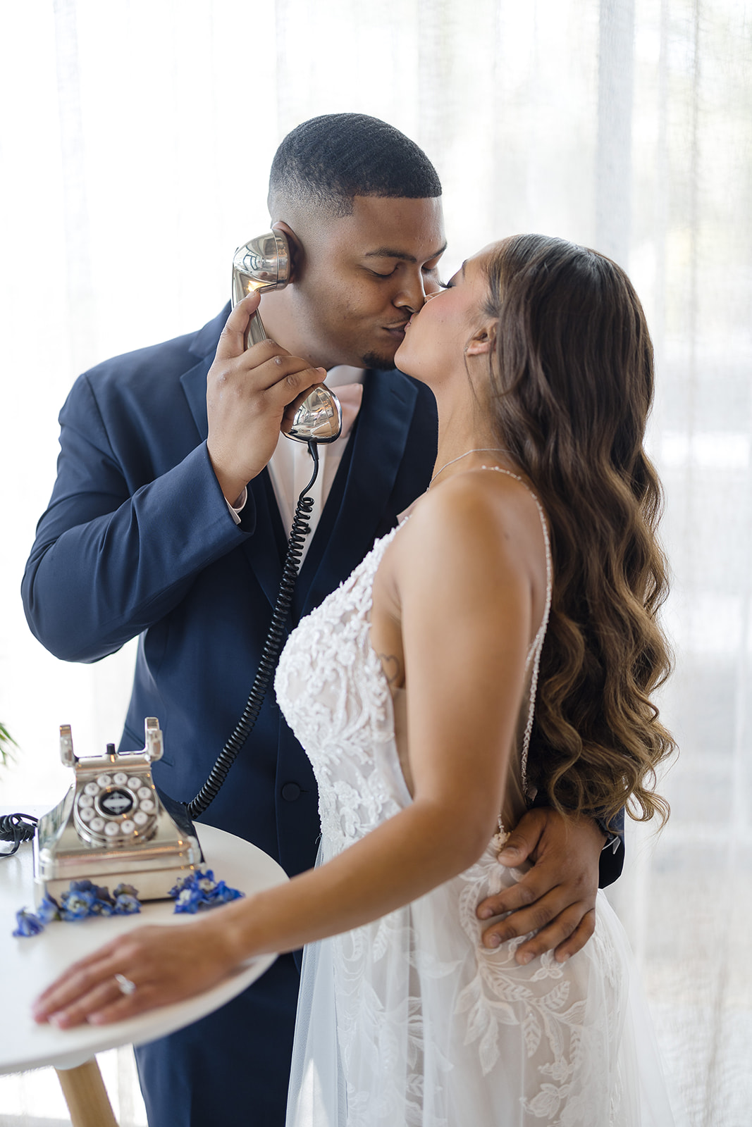 Bride and groom sharing a kiss beside the Well Wishes vintage audio guestbook